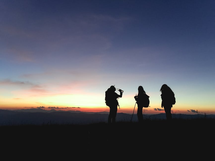 Group of hikers silhouetted against a vibrant sunset