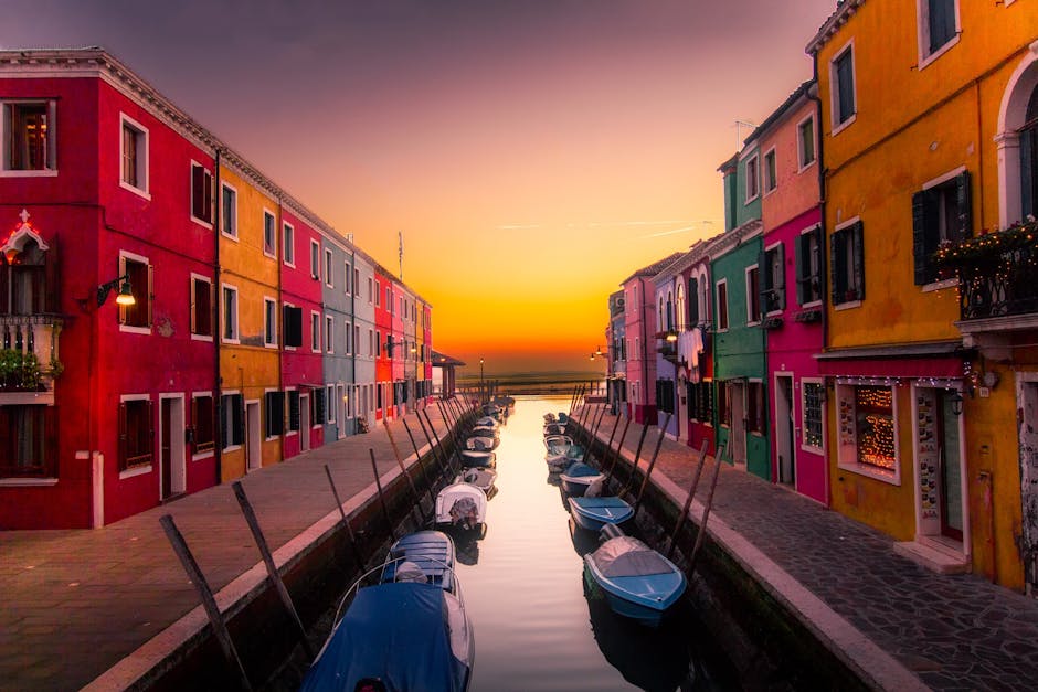 Vibrant facades along Burano's canal with boats at sunset